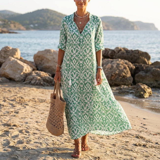 FJØRNA floral V-neck maxi dress with short sleeves and flowy fit, featuring a vibrant floral pattern and lightweight fabric.