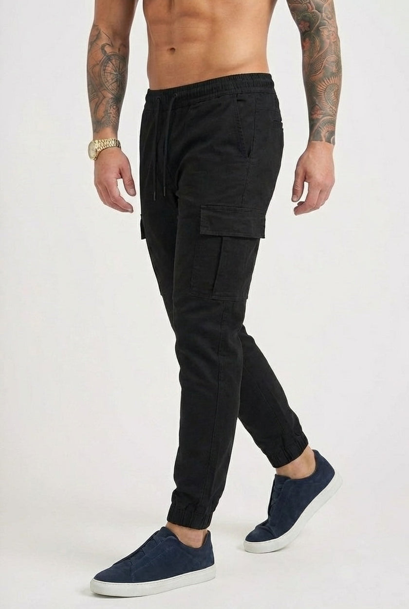 Men's black cargo jogger trousers by FJØRNA with multiple pockets and tapered fit, shown on a model.