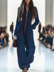 Dark blue FJØRNA denim wide-leg jumpsuit with long sleeves and topstitched details, shown as women's pants in the image.