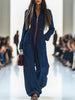 Dark blue FJØRNA denim wide-leg jumpsuit with long sleeves and topstitched details, shown as women's pants in the image.