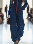 Dark blue FJØRNA women's denim jumpsuit with topstitching, wide-leg pants, and long sleeves, styled with a casual fit.