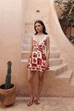 FJØRNA Leila printed cut-out mini dress in white with bold red sunfere pattern, stylish and suitable for warm-weather wear.