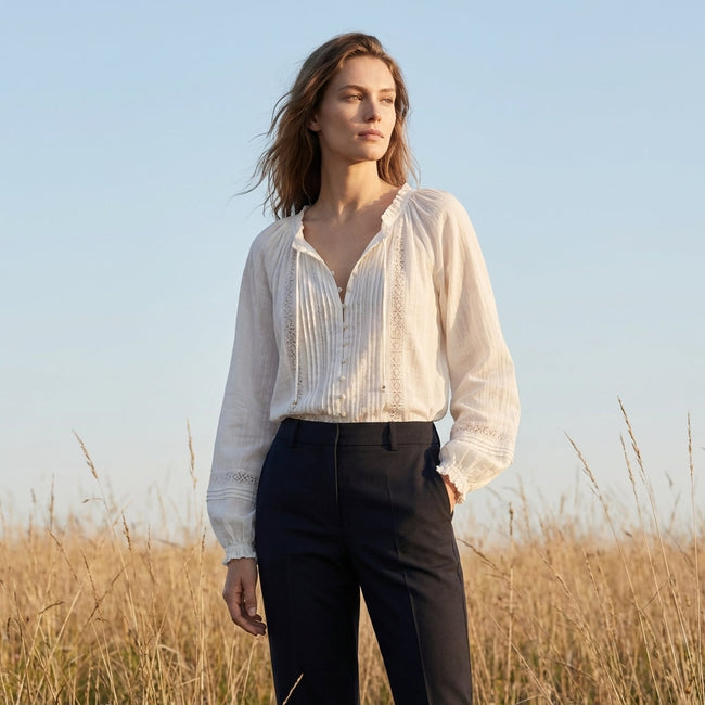 FJØRNA summer women's blouse featuring a V-neck, long sleeves, lace details, and ruffle accents in a casual lifestyle setting.