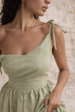 Sage green boho maxi dress by FJØRNA featuring flowing fabric and bohemian style, displayed on a hanger against a neutral background.