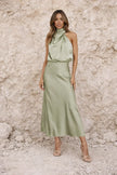 Sage green satin dress by FJØRNA featuring a flowing design and elegant fabric, shown on a model in a stylish setting.