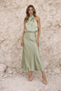 Sage green satin dress by FJØRNA featuring a flowing design and elegant fabric, shown on a model in a stylish setting.