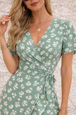 Sage green FJØRNA wrap dress with a front slit, flowing fabric, and elegant silhouette, perfect for stylish occasions.