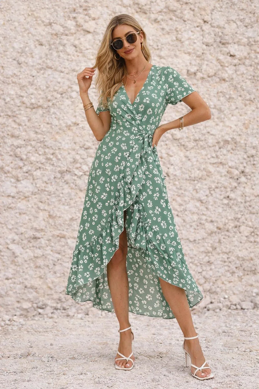 Sage green FJØRNA wrap dress with a slit, featuring a flattering neckline and flowing fabric, styled for elegant occasions.