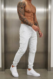 Men's cargo jogger trousers in stone color by FJØRNA, featuring relaxed fit and multiple pockets, shown on a model.