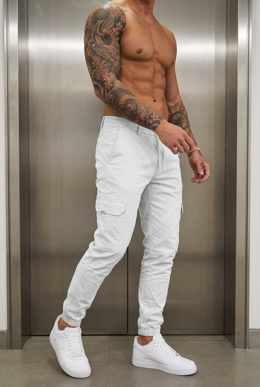 Men's cargo jogger trousers in stone color by FJØRNA, featuring relaxed fit and multiple pockets, shown on a model.
