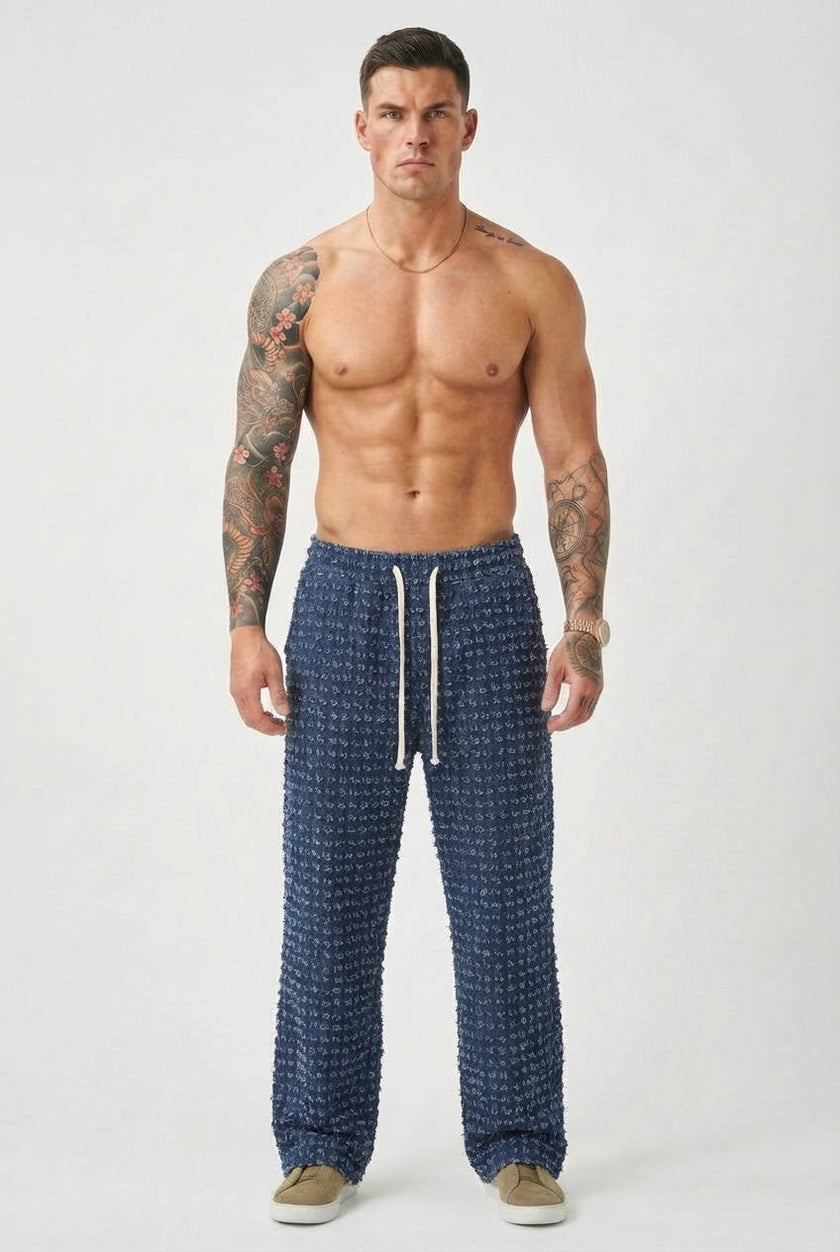 Black distressed men's trousers by FJØRNA, showing a slim fit design with ripped details and casual style.