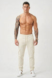 Men's FJØRNA cargo jogger trousers in cream, featuring relaxed fit, multiple pockets, and comfortable cotton fabric.