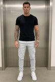 Men's cargo jogger trousers in stone color by FJØRNA, featuring a relaxed fit and multiple utility pockets.