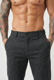 Black slim-fit men's trousers from FJØRNA, showing a close-up of the tailored fabric and sleek design.