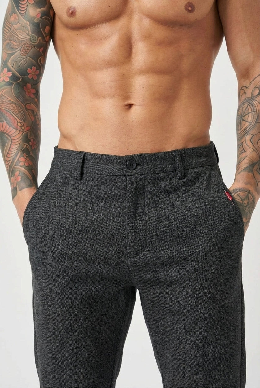 Black slim-fit men's trousers from FJØRNA, showing a close-up of the tailored fabric and sleek design.