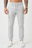 Men's cargo jogger trousers in stone color by FJØRNA, featuring relaxed fit and functional pockets, shown on a model.