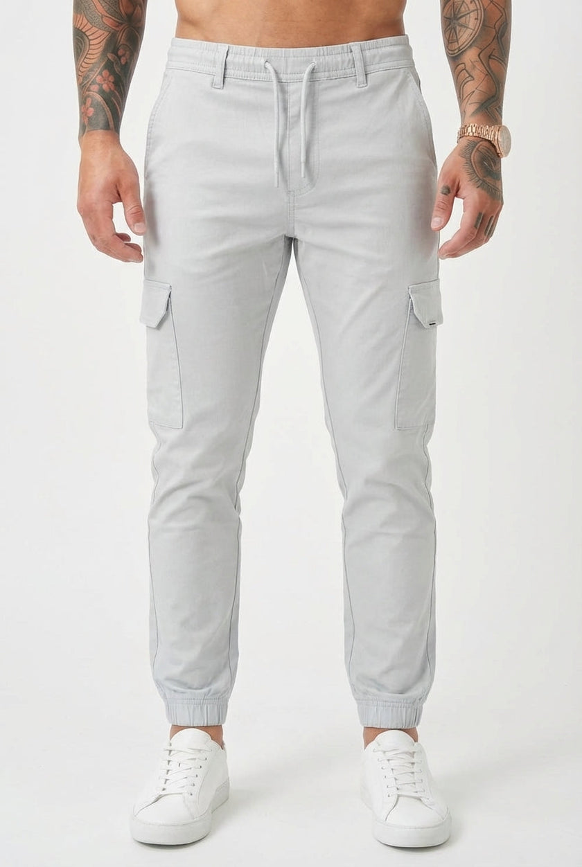 Men's cargo jogger trousers in stone color by FJØRNA, featuring relaxed fit and functional pockets, shown on a model.