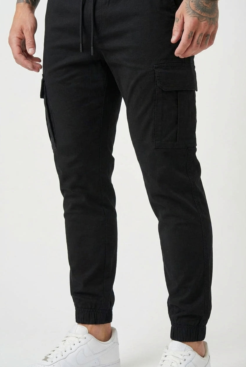 Men's black cargo jogger trousers by FJØRNA, featuring multiple pockets and a relaxed fit, shown on a model.