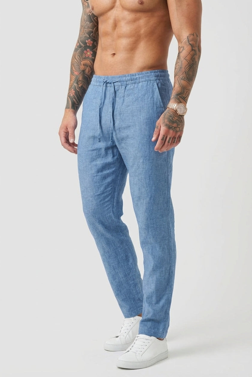 Men's beige relaxed linen trousers by FJØRNA, shown on a model, featuring a comfortable fit and lightweight fabric.