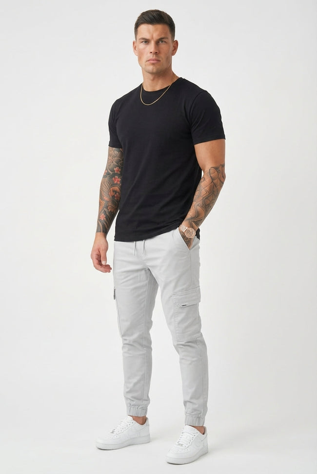 Men's cargo jogger trousers in stone from FJØRNA, featuring relaxed fit and functional pockets, displayed on a model.