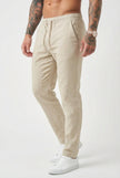 Men's beige relaxed linen trousers by FJØRNA, featuring a comfortable fit and casual style, displayed on a model.
