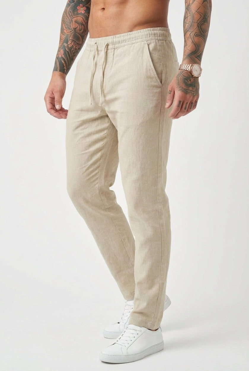 Men's beige relaxed linen trousers by FJØRNA, featuring a comfortable fit and casual style, displayed on a model.