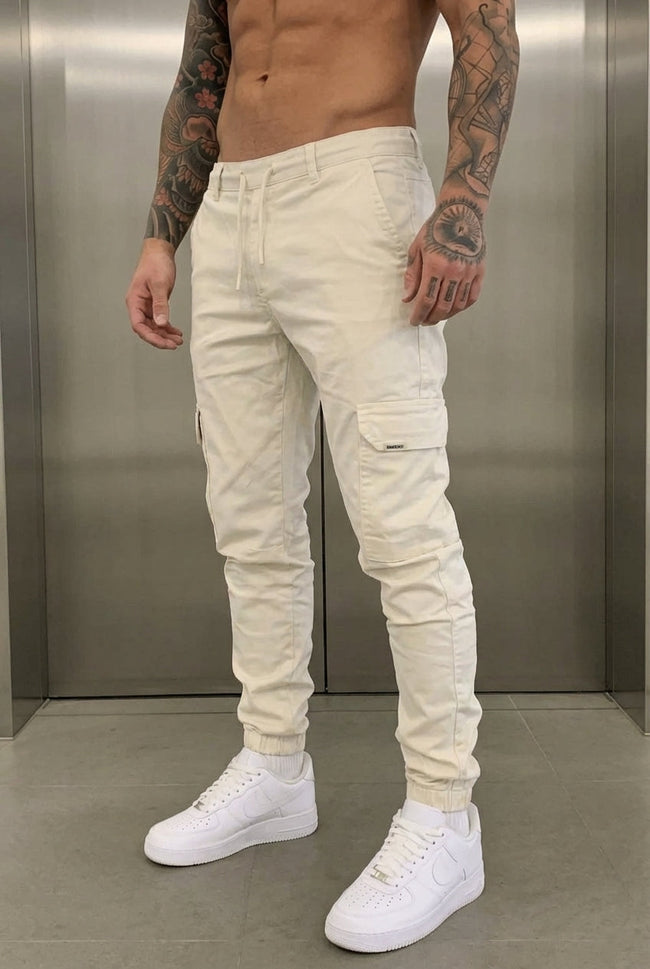 Cream cargo jogger trousers for men by FJØRNA, featuring relaxed fit and multiple pockets, displayed on a model.