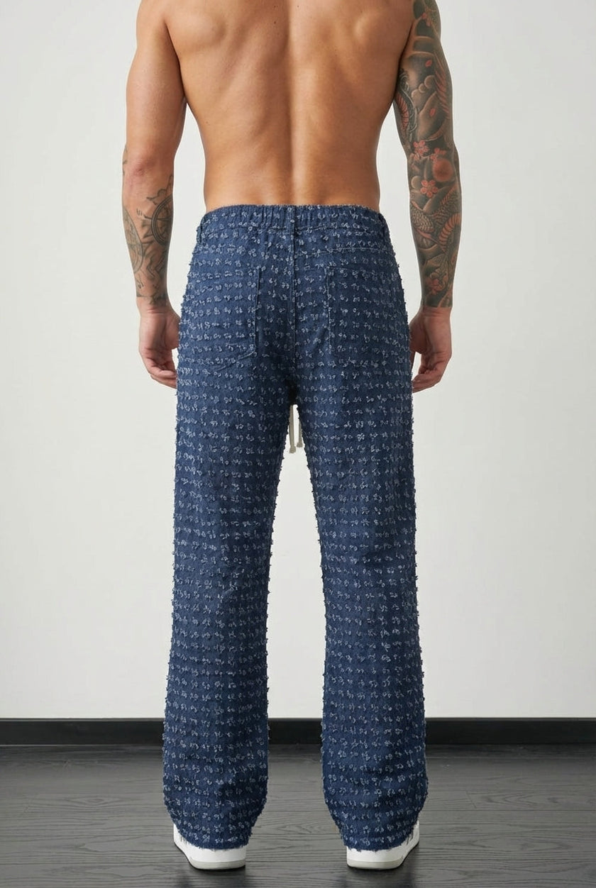 Black distressed men's pants by FJØRNA, featuring a casual fit and worn-in distressed detailing, shown on a model.