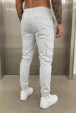 Men's cargo jogger trousers in stone color by FJØRNA, shown in a relaxed fit with multiple cargo pockets.