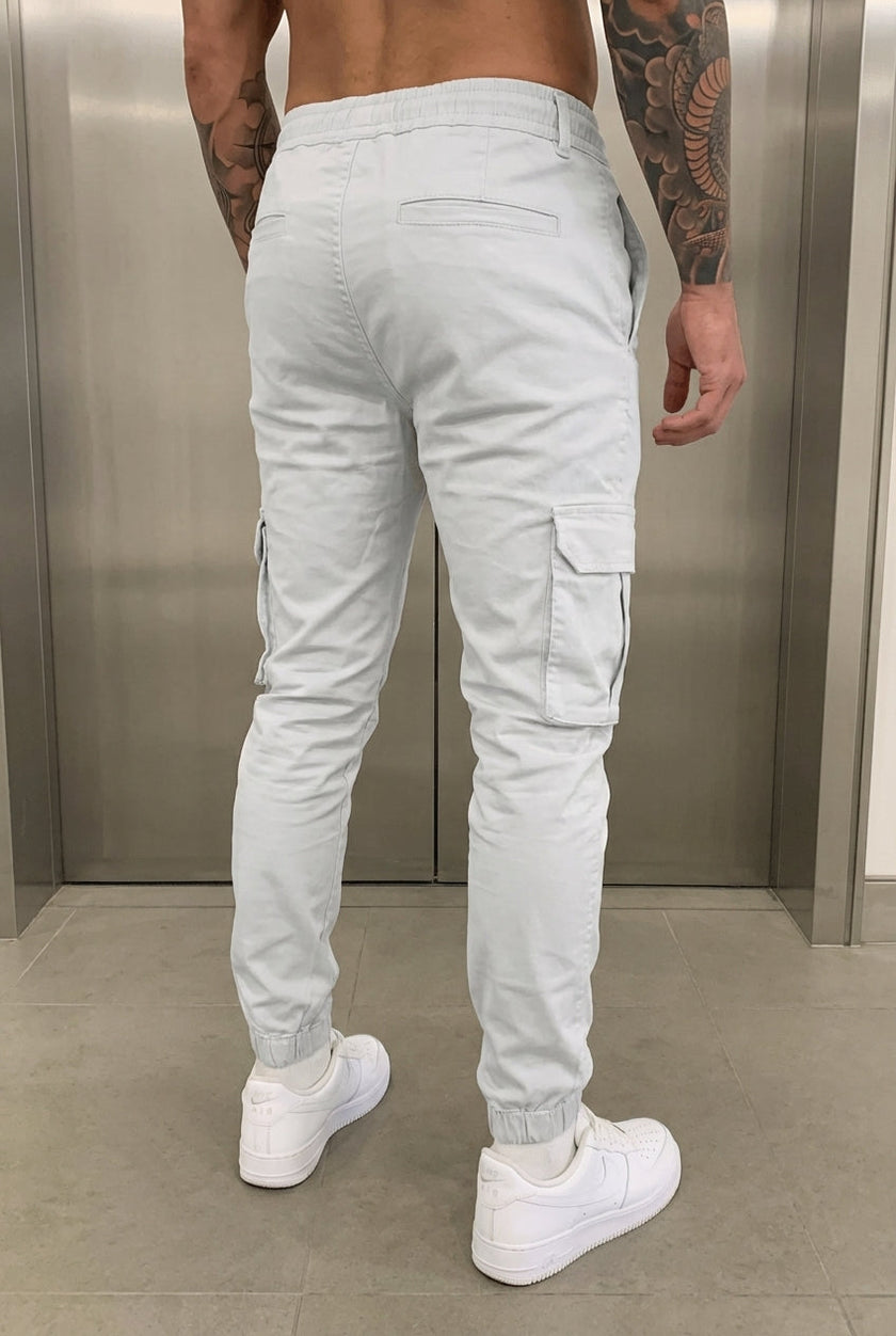 Men's cargo jogger trousers in stone color by FJØRNA, shown in a relaxed fit with multiple cargo pockets.